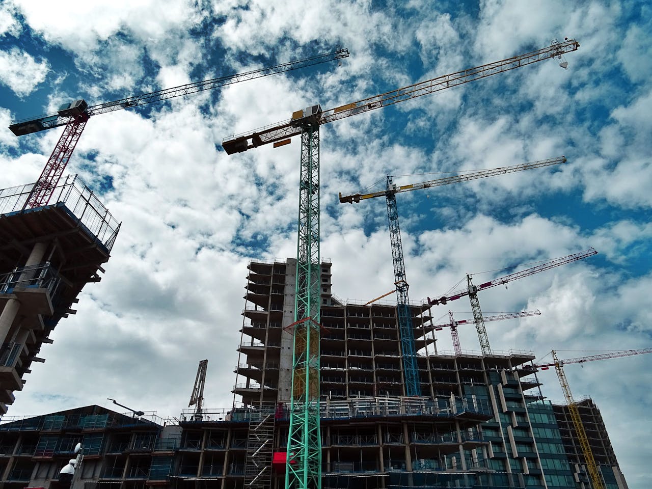 hero-contact Urban construction site with numerous cranes framing rising skyscrapers against a blue sky.